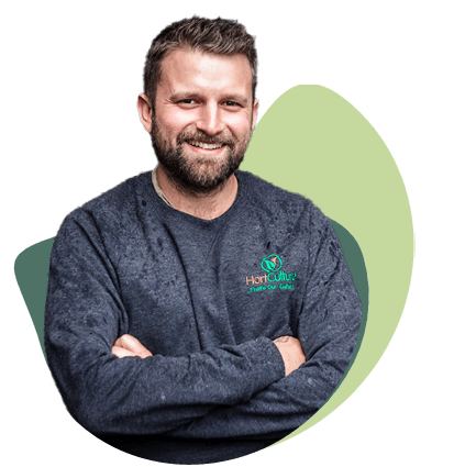 Isaac, Director of Hort Culture, arms crossed and smiling, in a Hort Culture jumper.